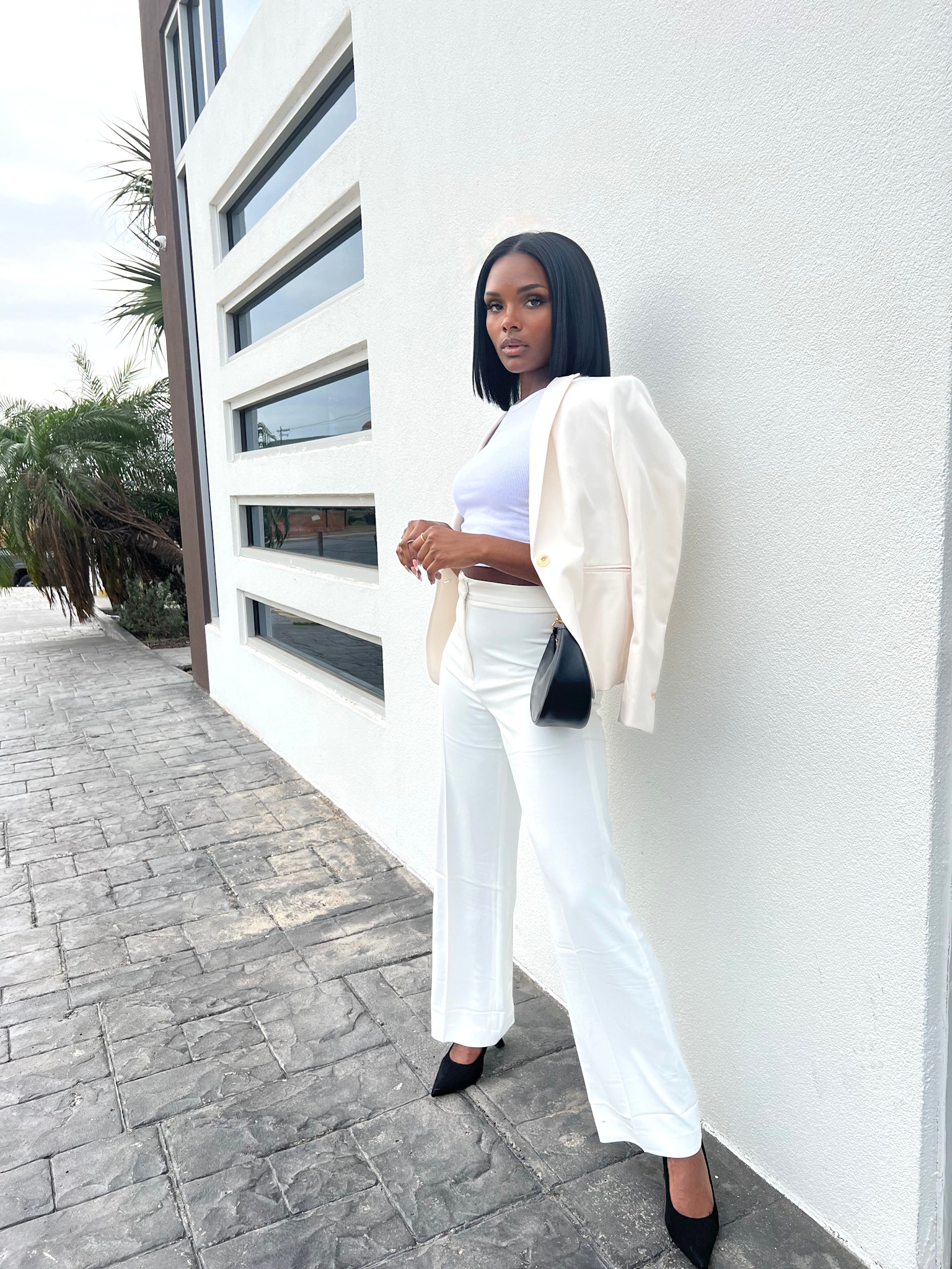 Full-length brand portrait of London in ivory tailoring and black accessories